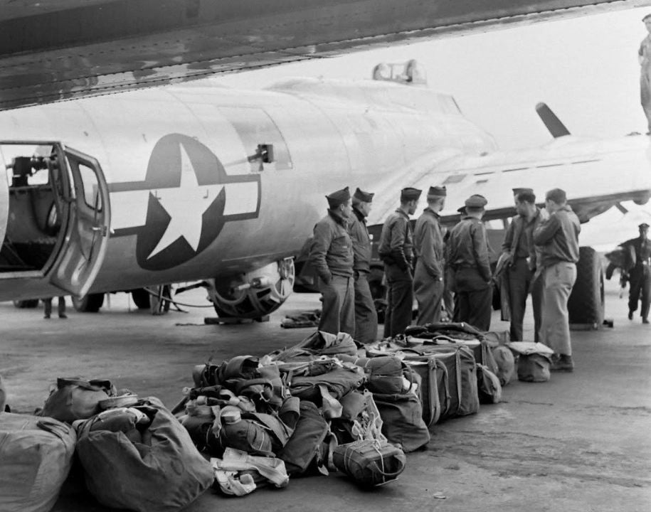 Skupinka amerických vojáků stojící s osobními věcmi u letadla